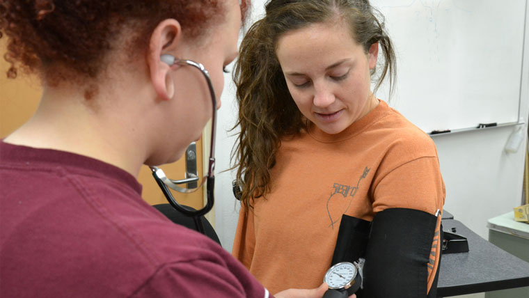 Student taking another student's blood pressure.