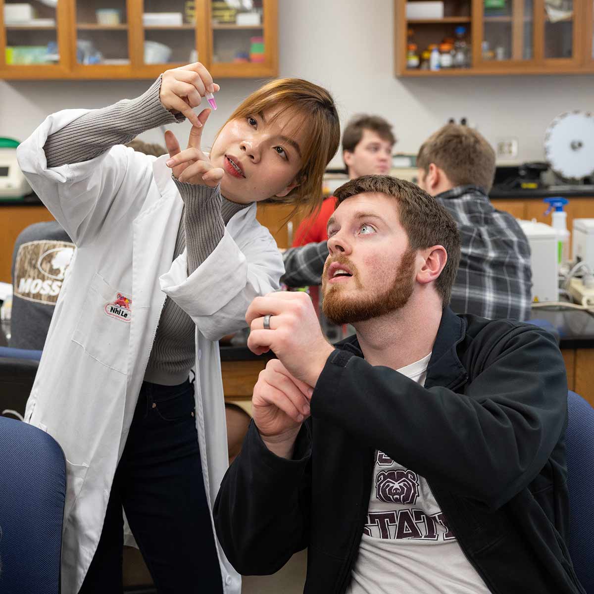 A biology teaching assistant instructing a student during a lab class.