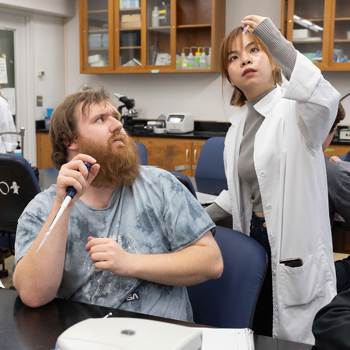 A graduate assistant helps a student with his lab work in a cell biology class.